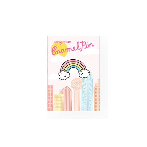 Colorful rainbow enamel pin with rubber backing on display card.